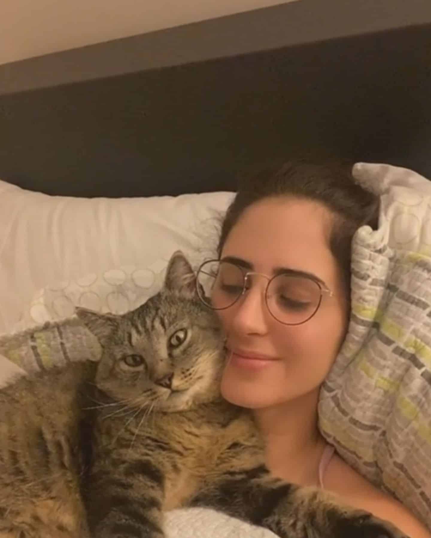woman with glasses laying down with cat