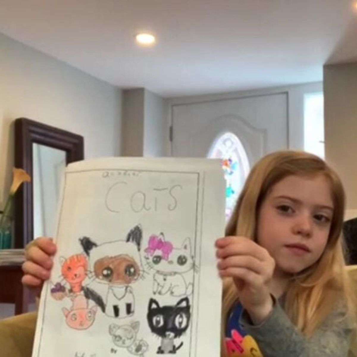 girl holding drawing of cats
