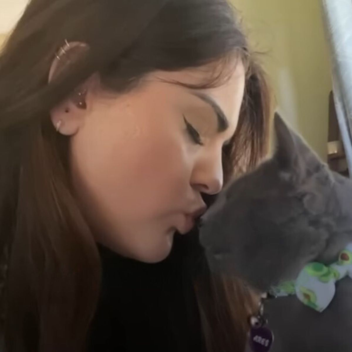 woman kissing a gray cat