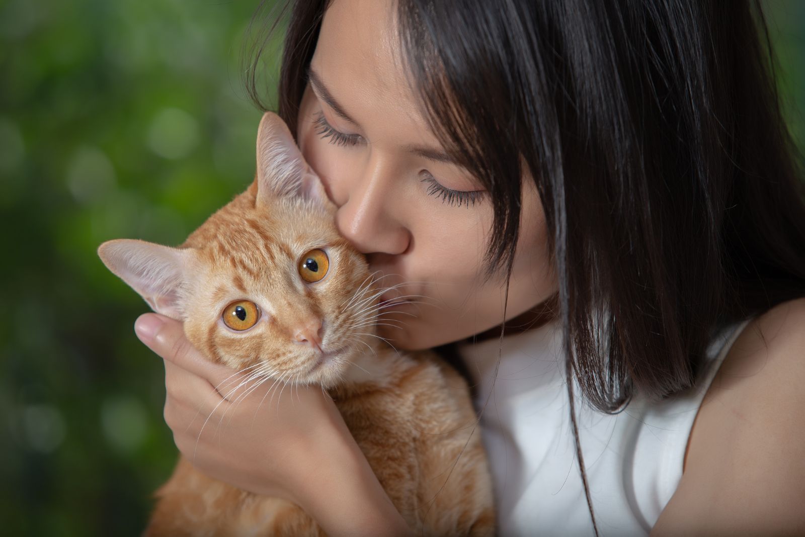 woman kissing ginger cat