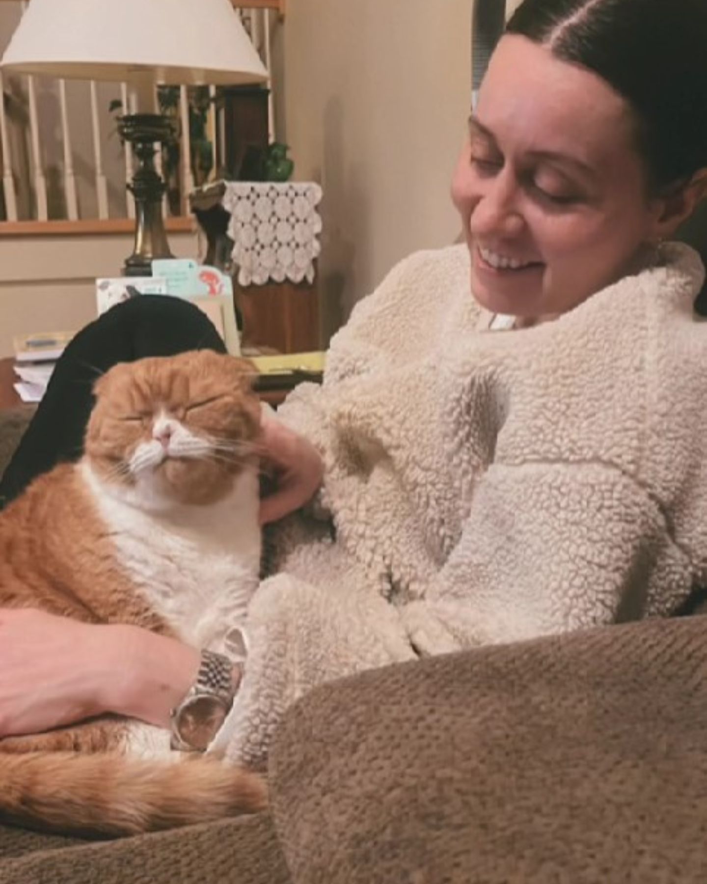 woman sitting on couch petting a cat