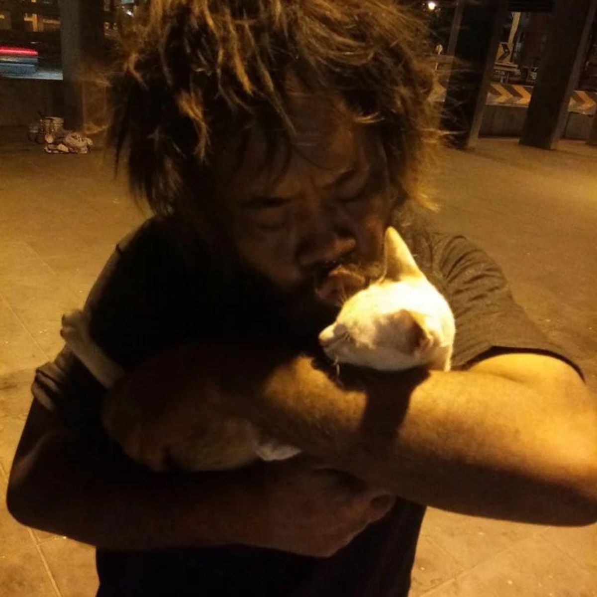 homeless guy kissing a cat