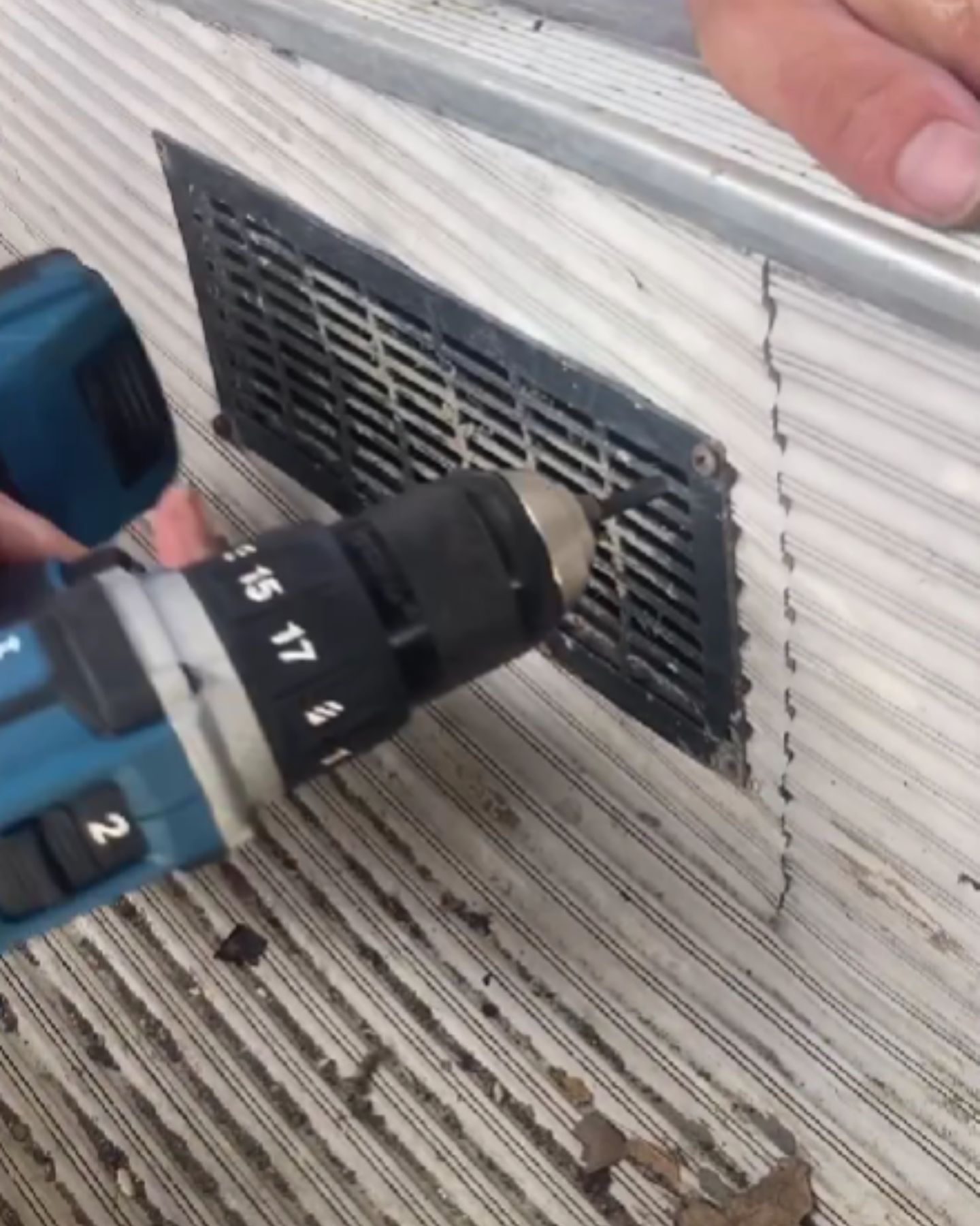 man opening up a vent with a drill