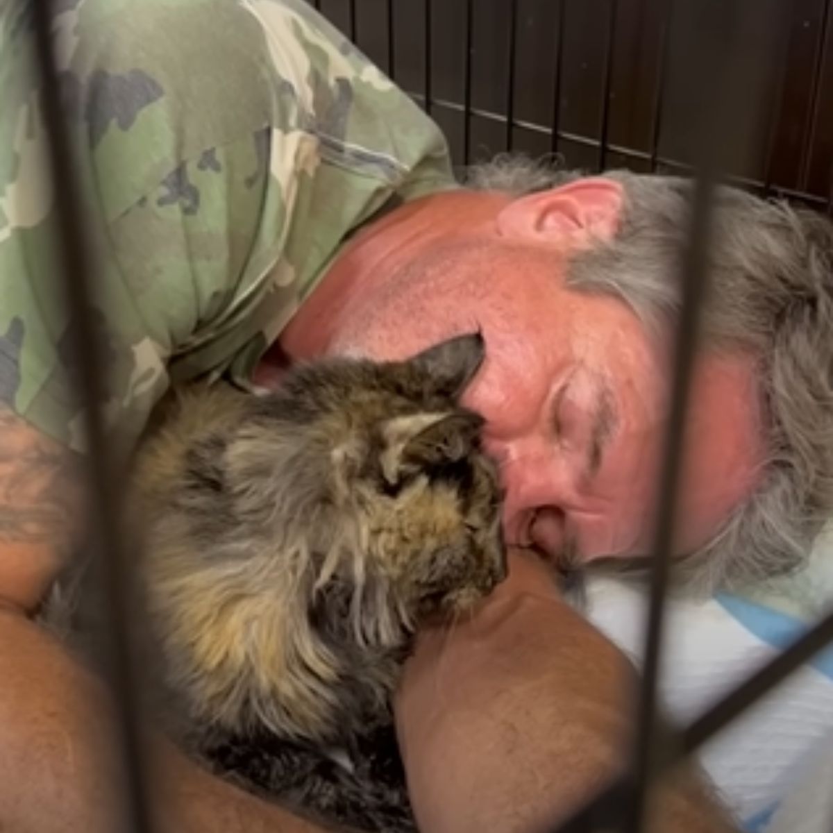 man sleeping with cat in cage