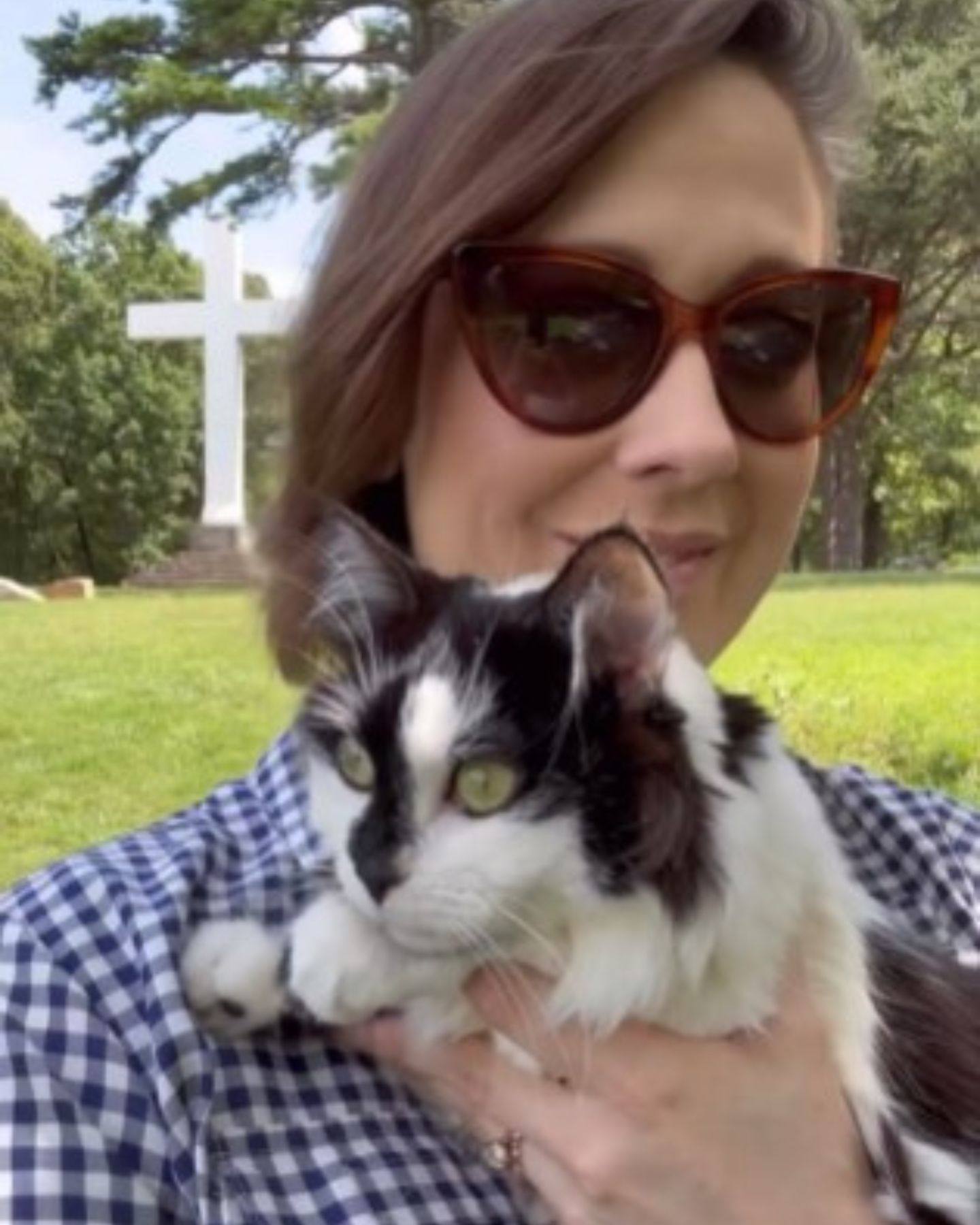 woman holding cat near cross