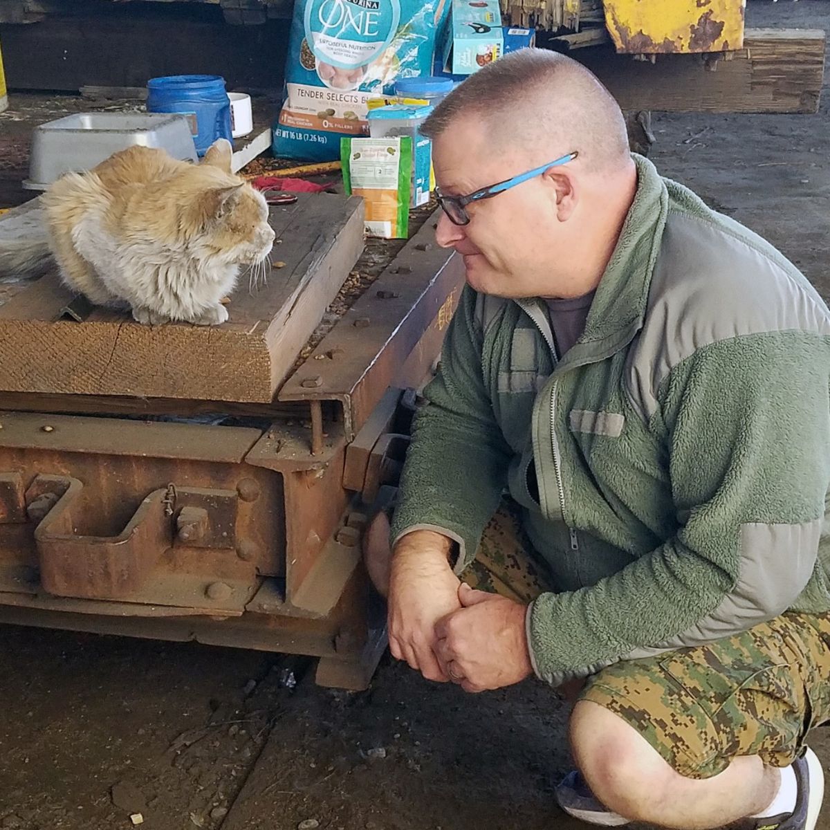 man squatting next to a cat