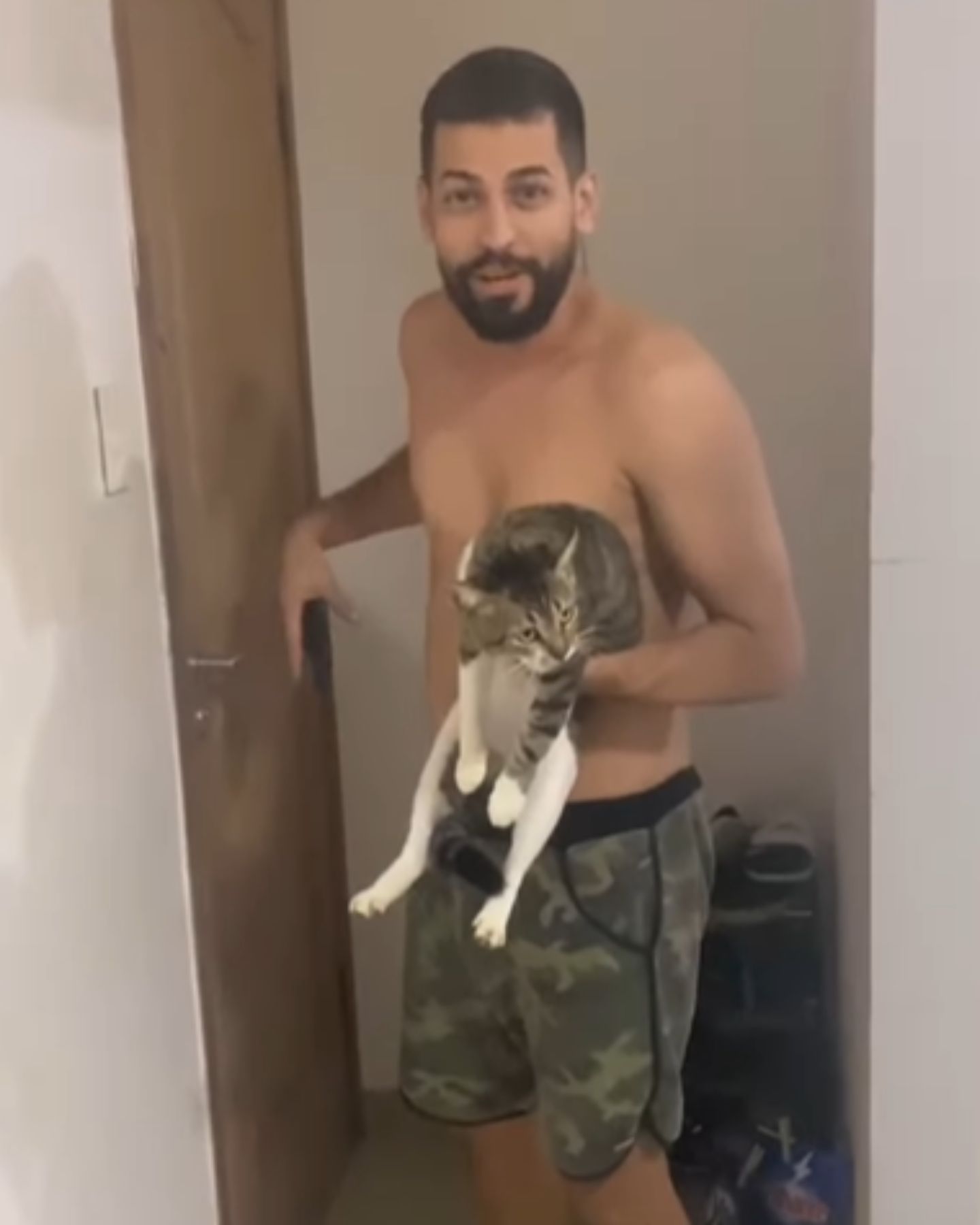 man without shirt bringing cat home