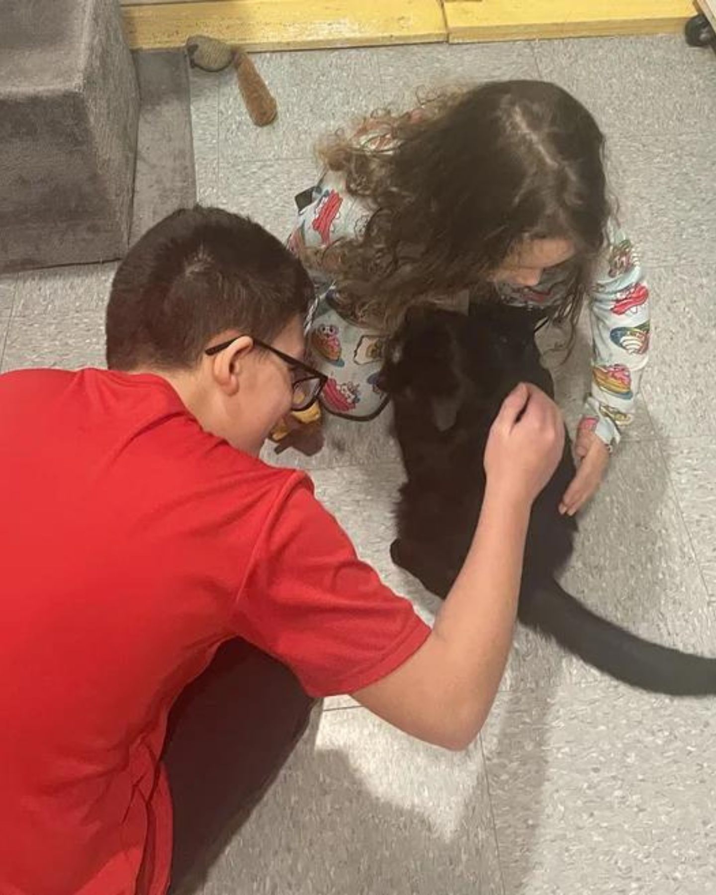 two kids playin with black cat