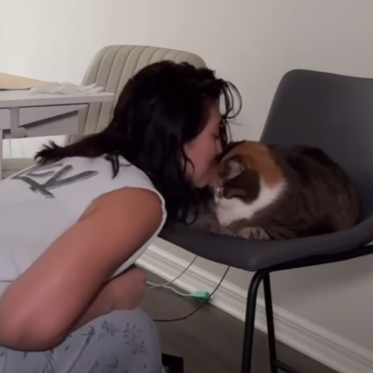 woman kissing cat in head
