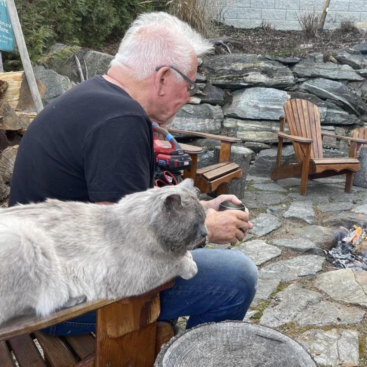 man and a cat sitting outdoors