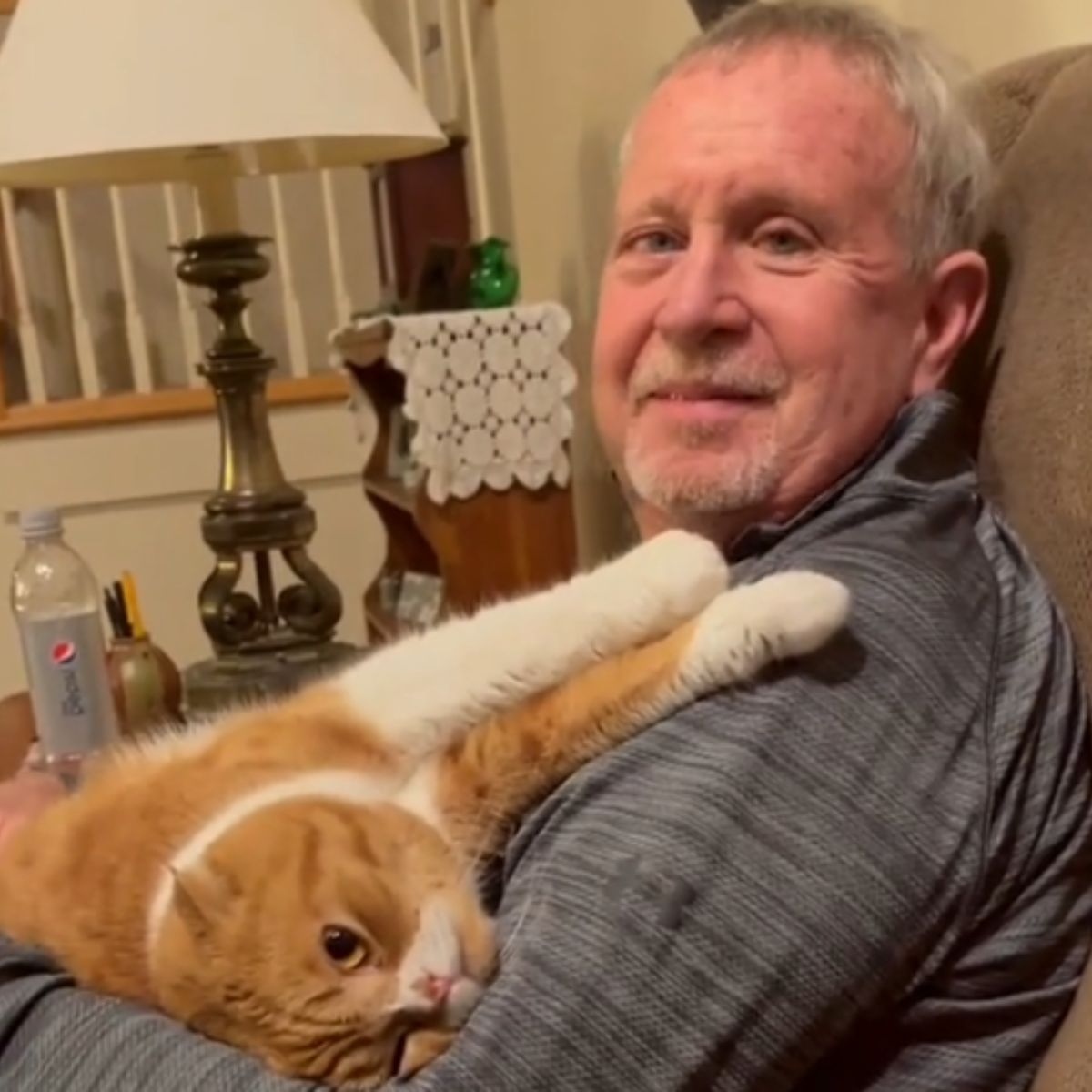 smiling man posing with cat on sofa