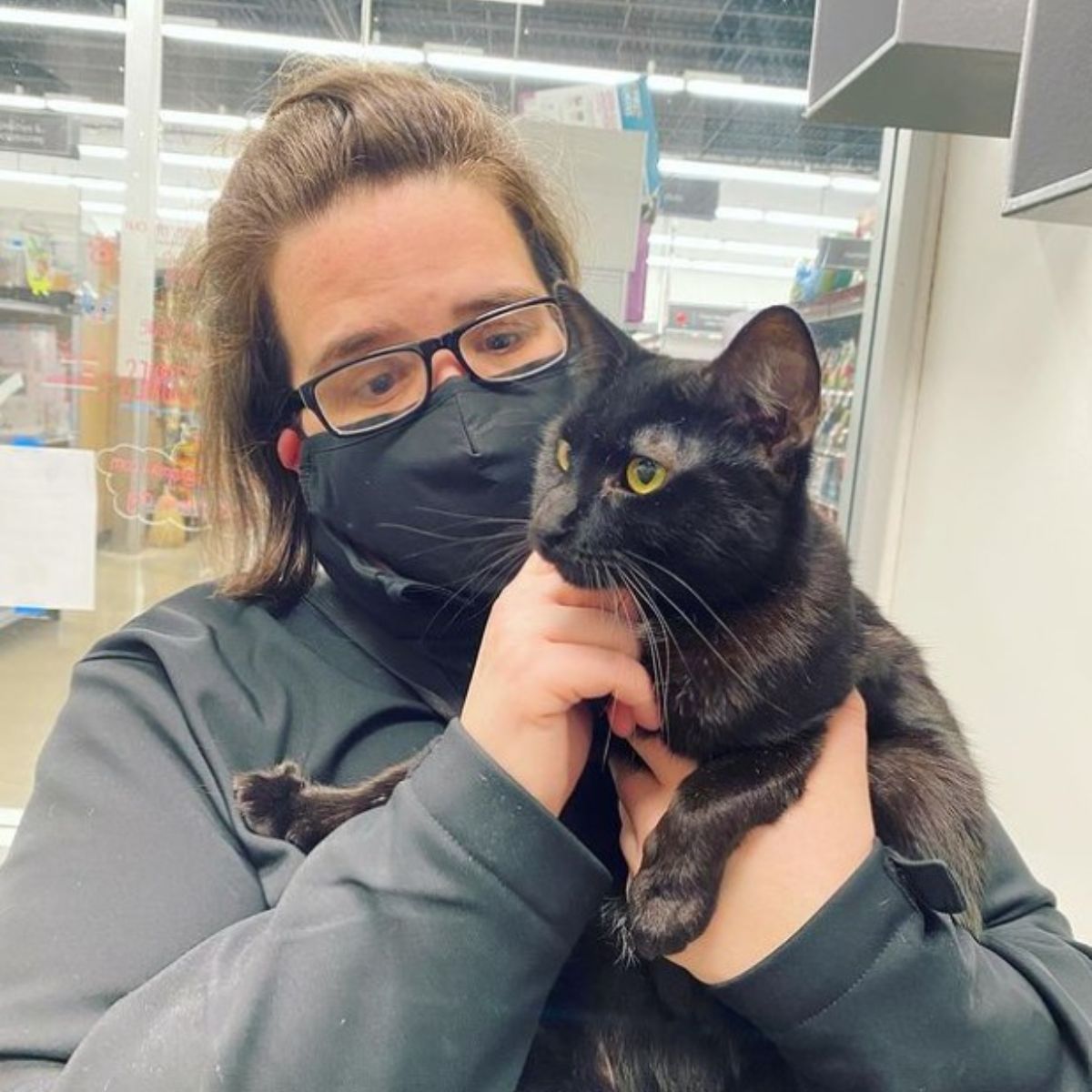 woman holding black cat in a store