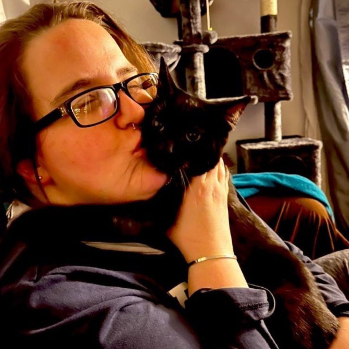 woman kissing a black cat