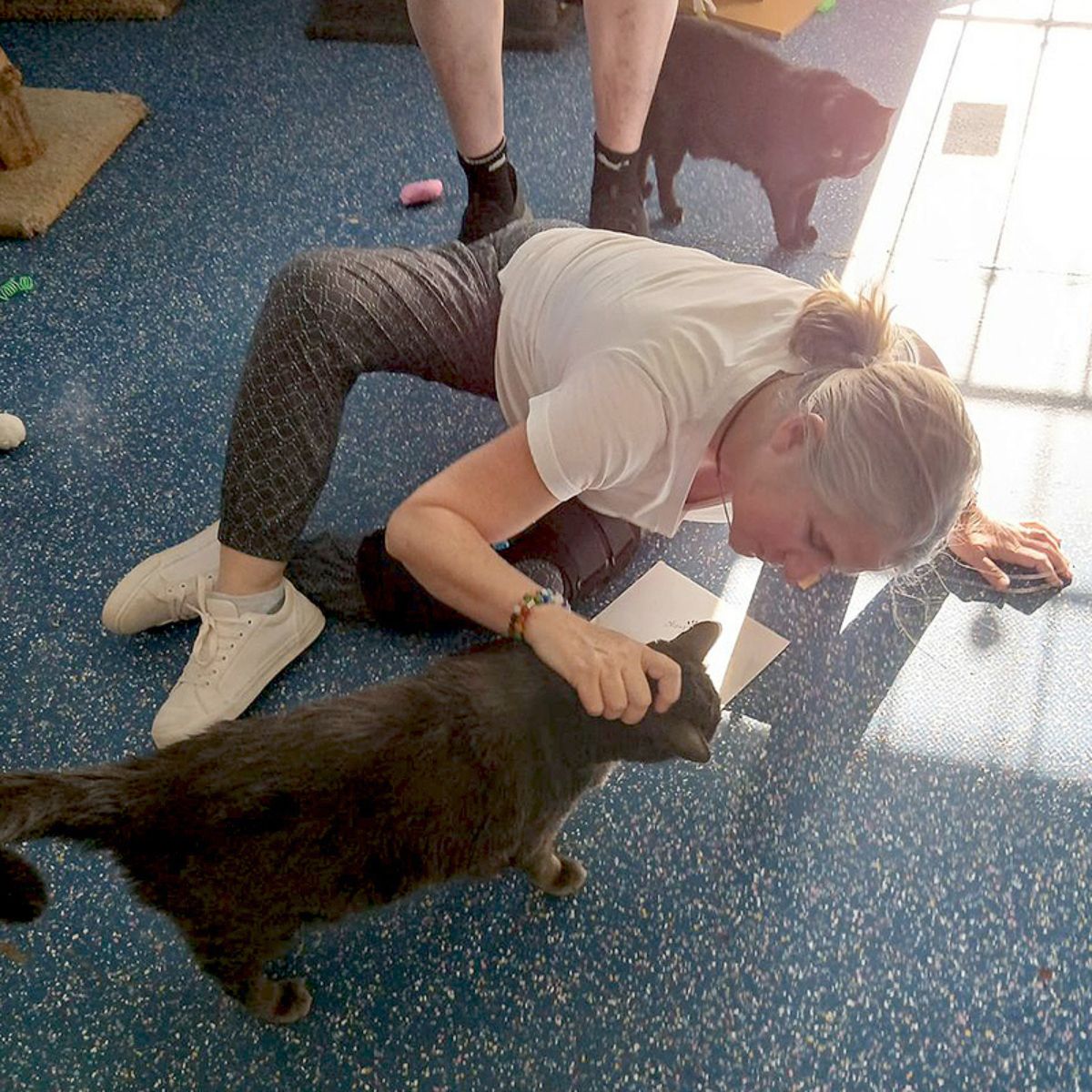 woman sitting on floor petting a cat