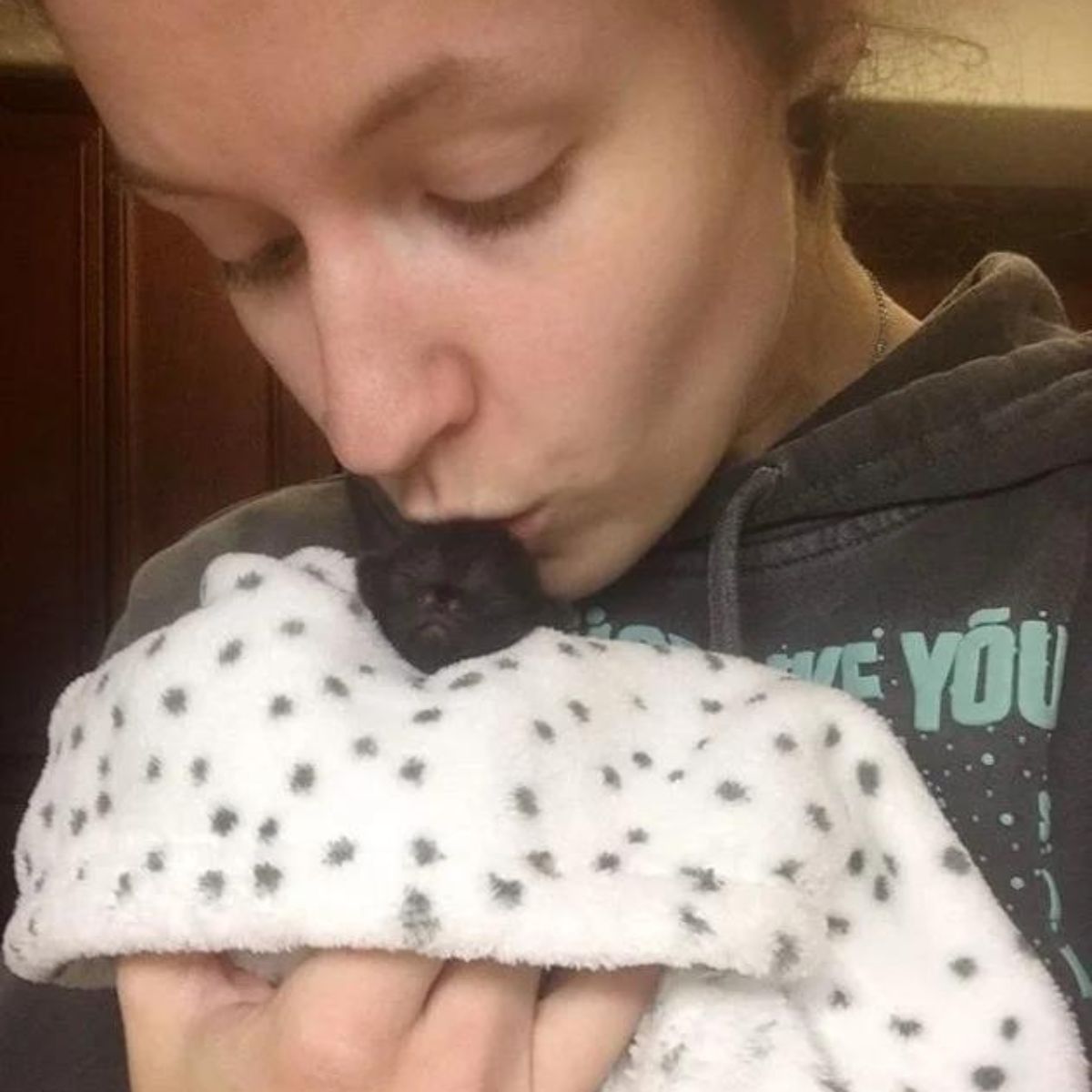 woman kissing newborn kitten