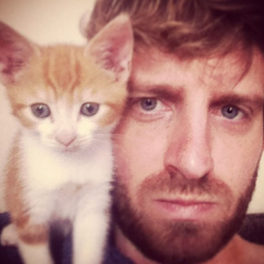 man and orange kitten in close-up