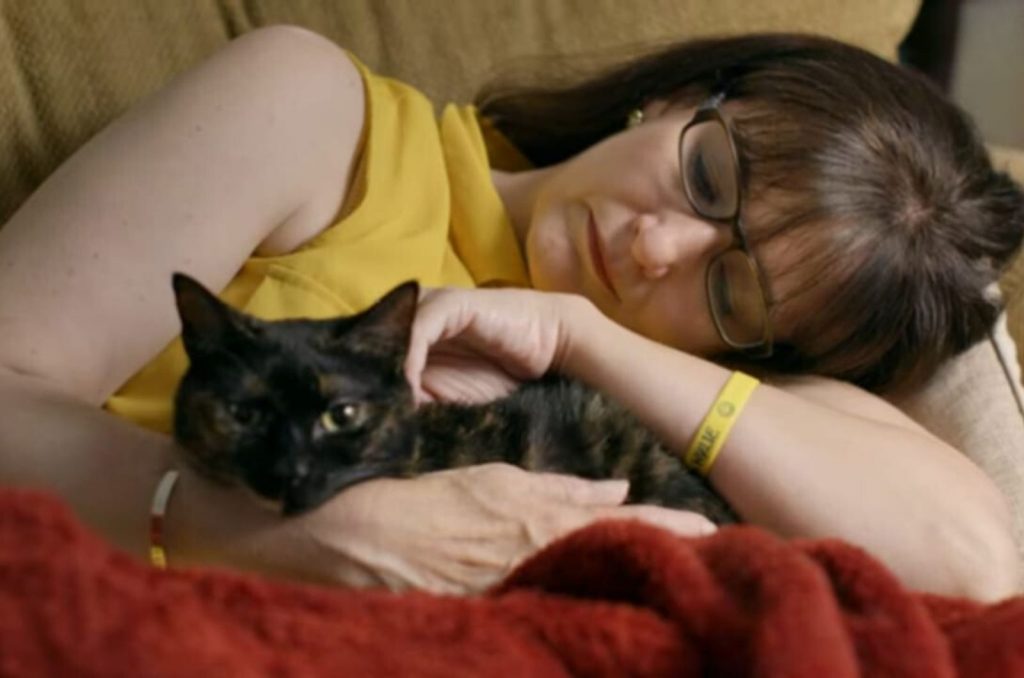 a woman lies and hugs a cat