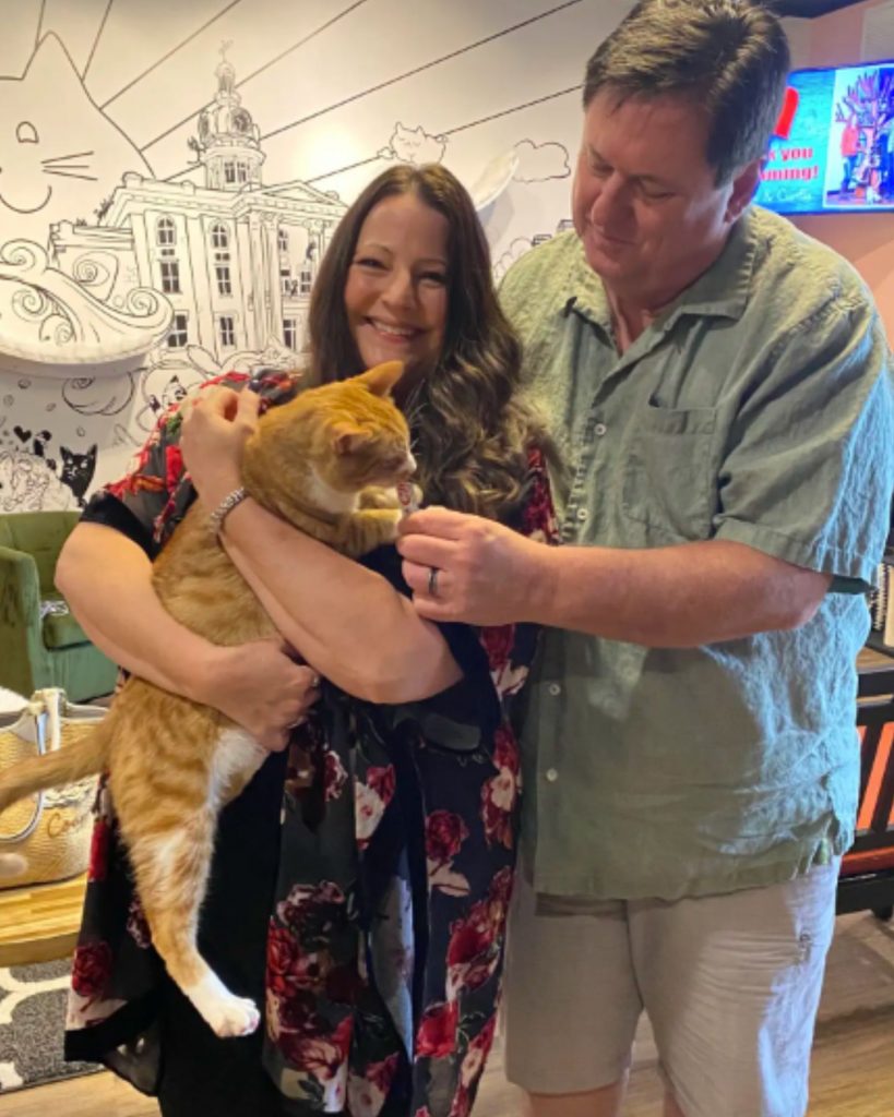 smiling married couple holding a cat in their arms