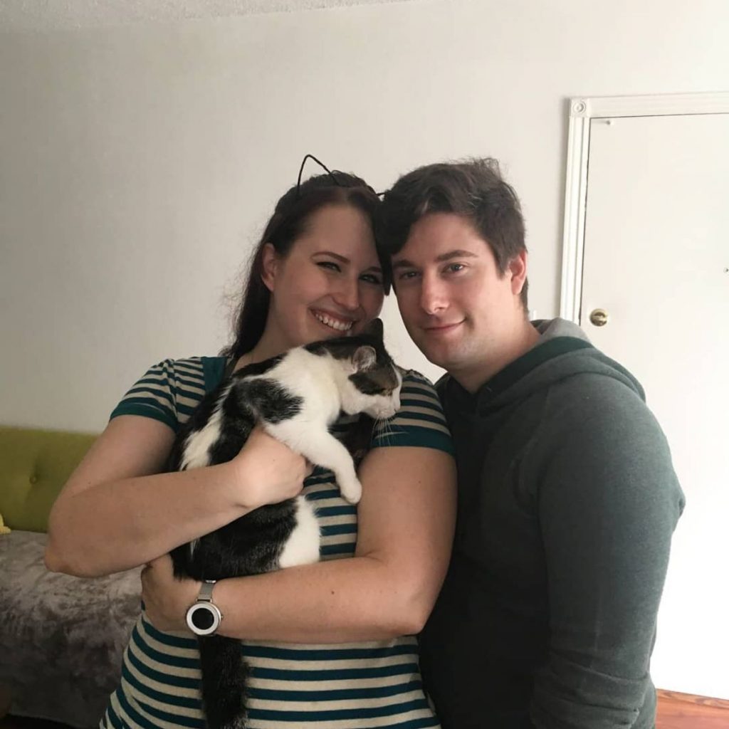 a man and a woman with a cat in their arms