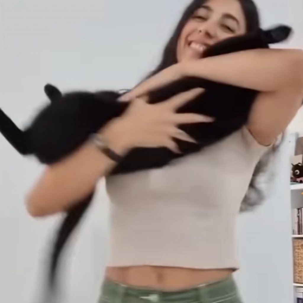 a smiling girl is holding a black cat in her arms