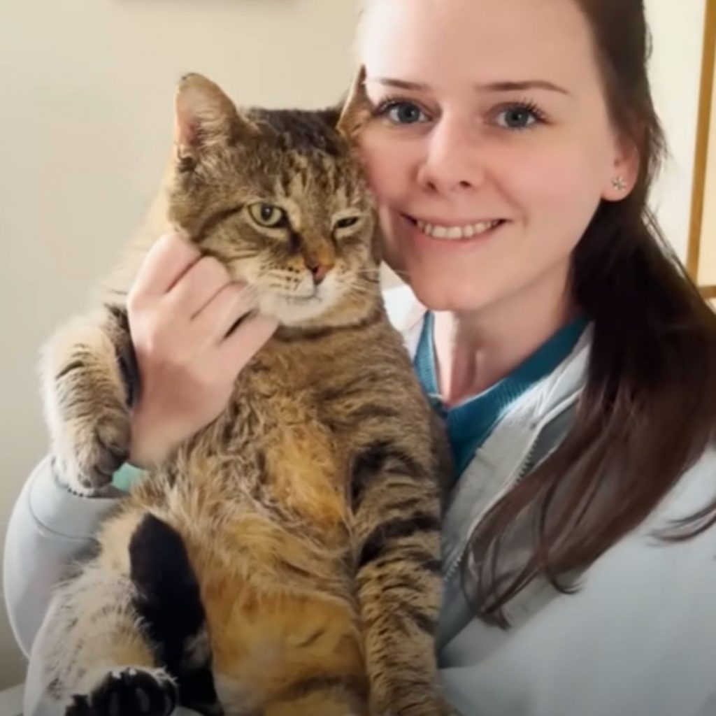 a smiling girl takes a picture with a cat in her arms