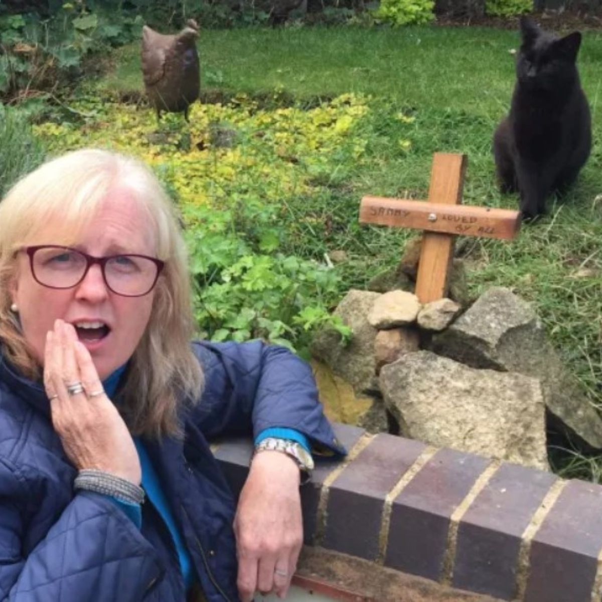 shocked woman posing with cat on grave