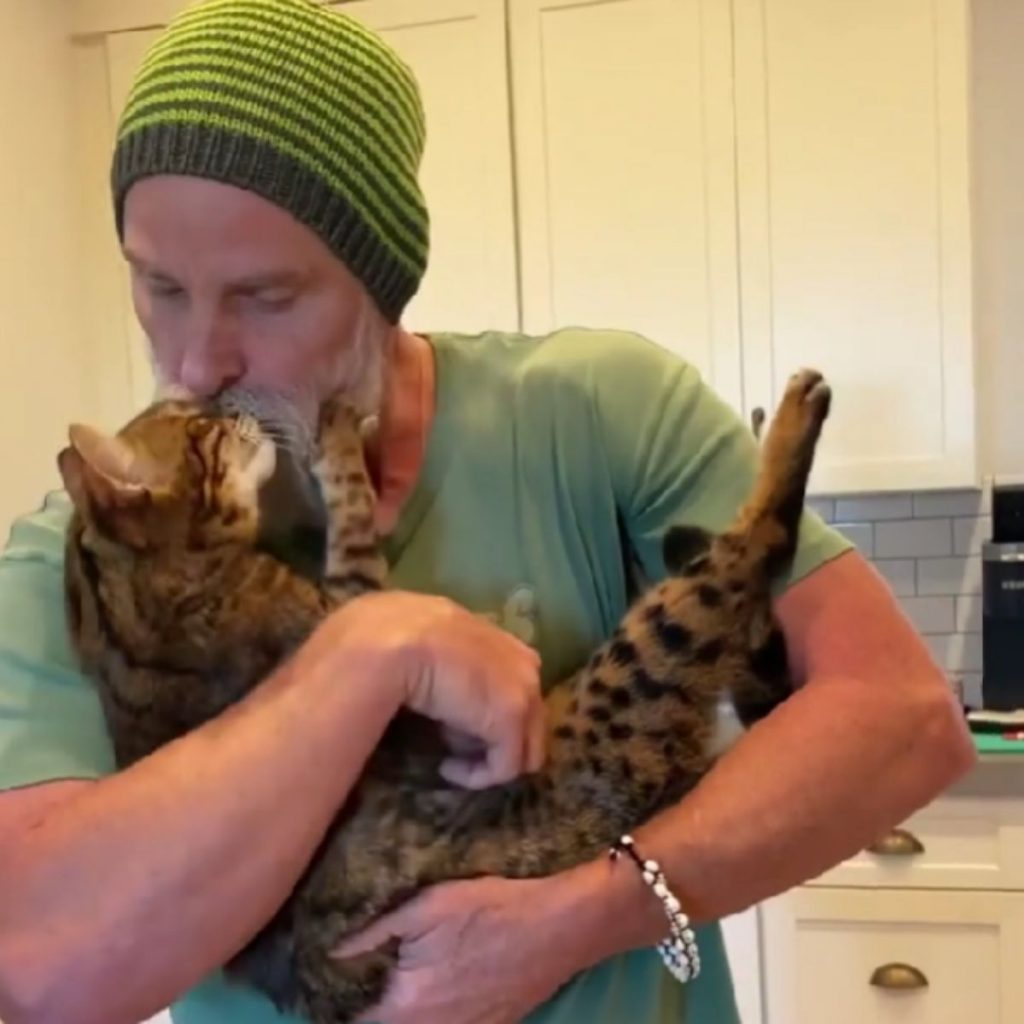 a man holds a cat in his arms and kisses it