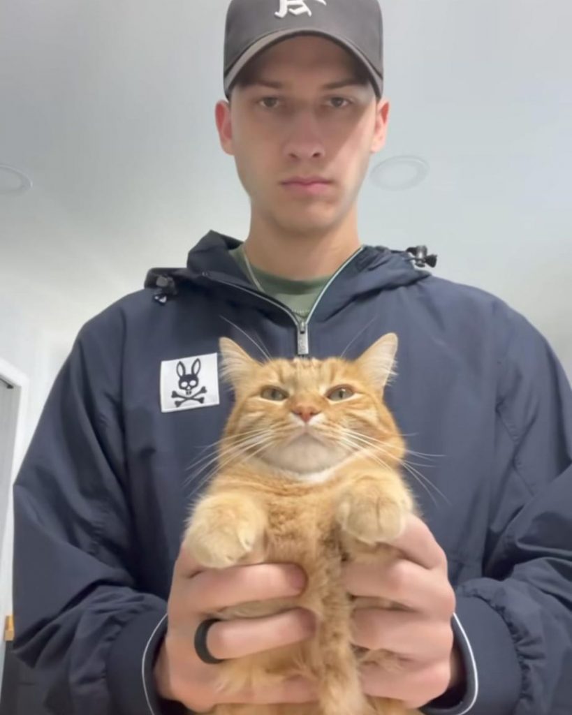 a man holds a yellow cat in his hands