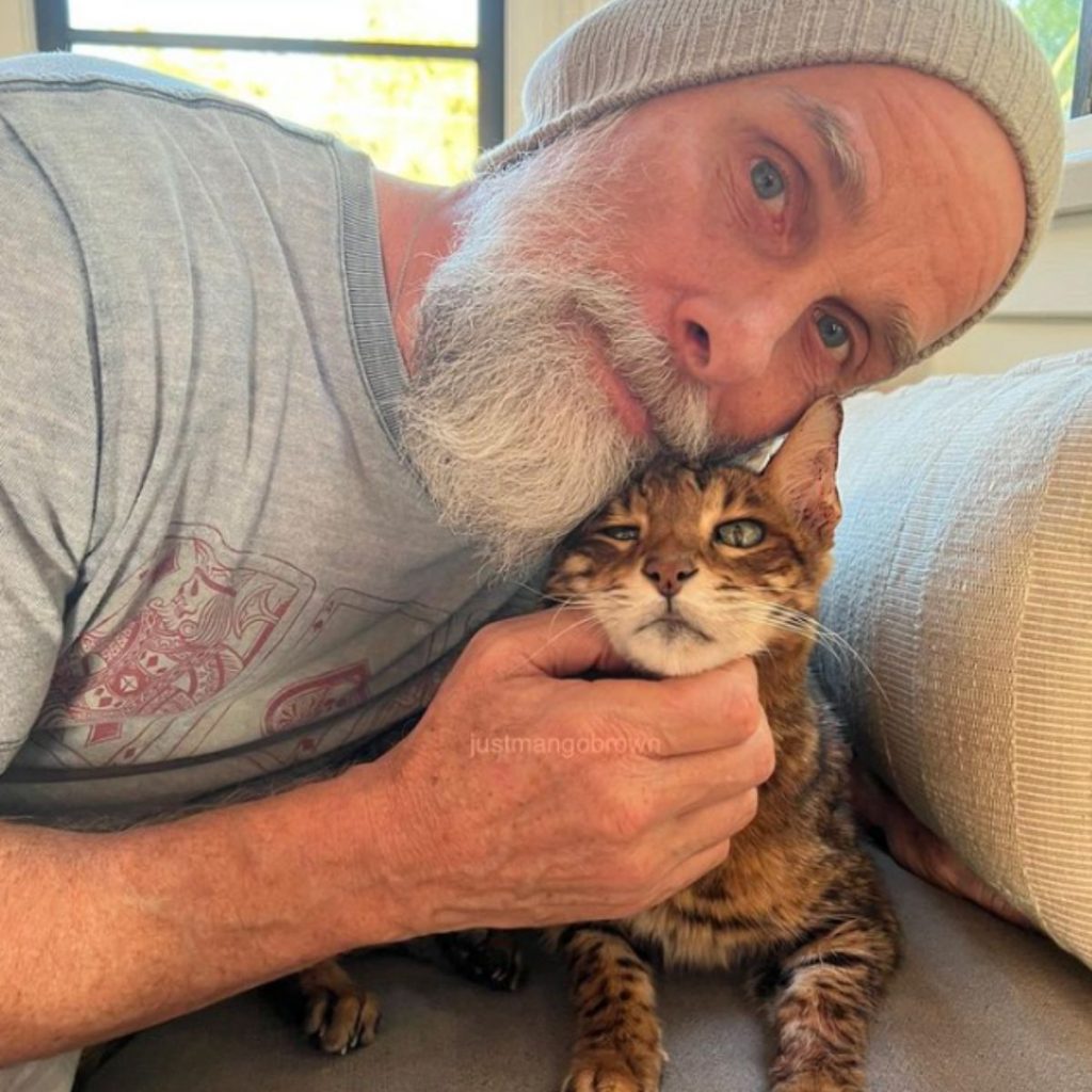 a man takes a picture with a bengal cat