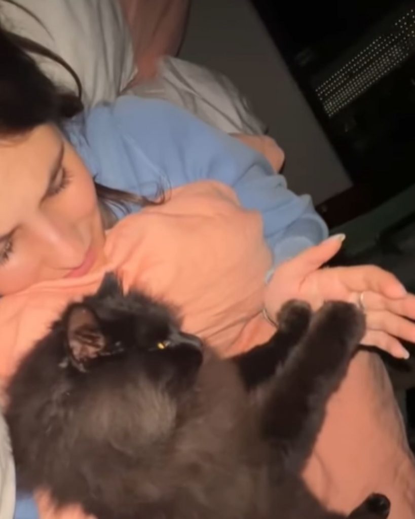 a woman cuddles with a black cat in bed