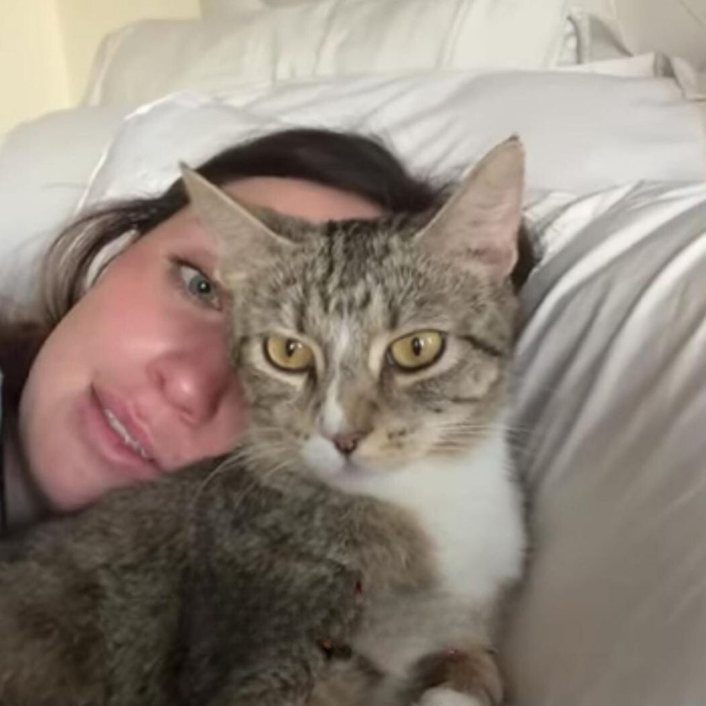 a woman lies in bed with a cat