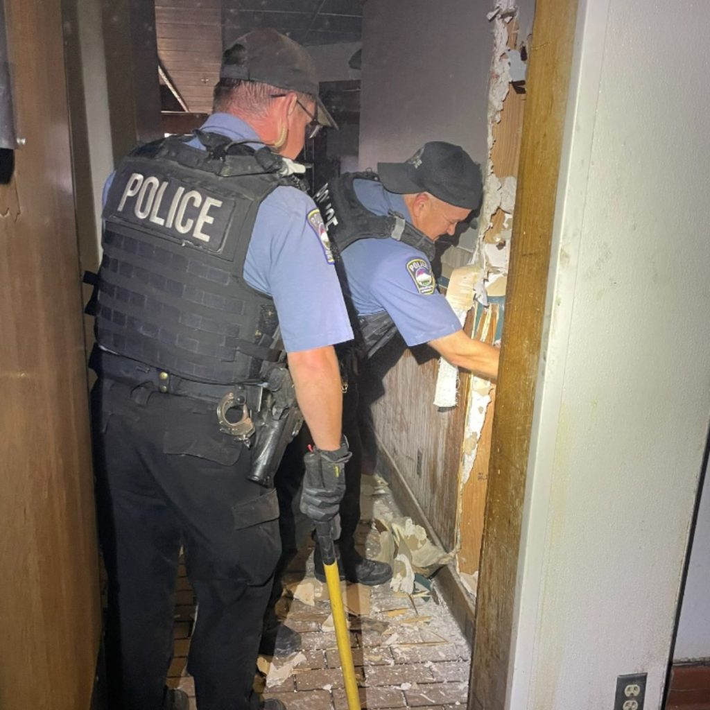 police officers inspect an abandoned house