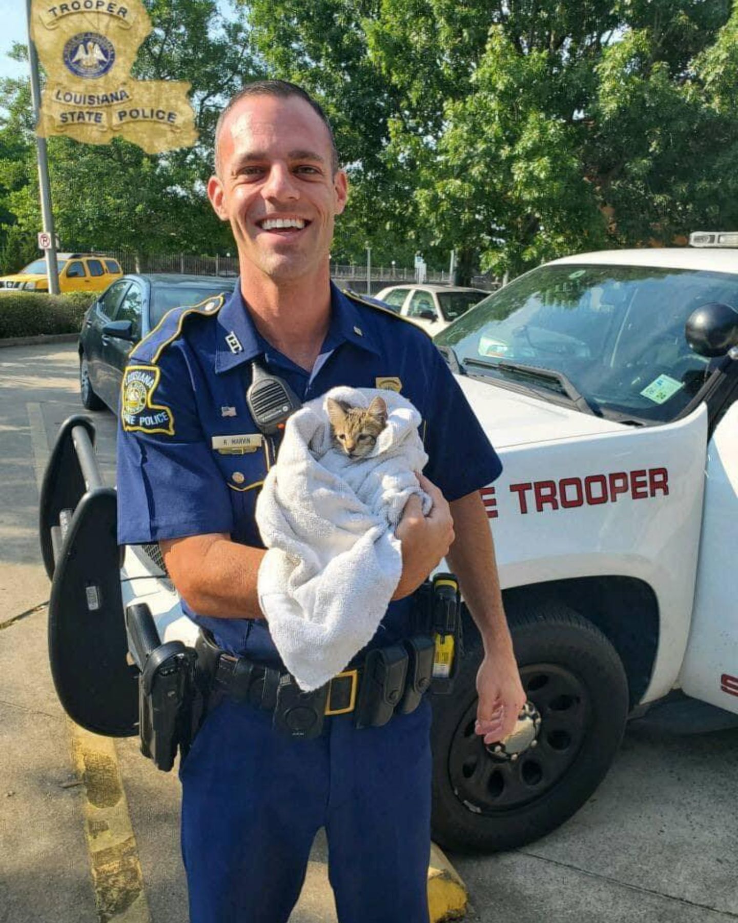 smiling police officer holding a cat in blanket