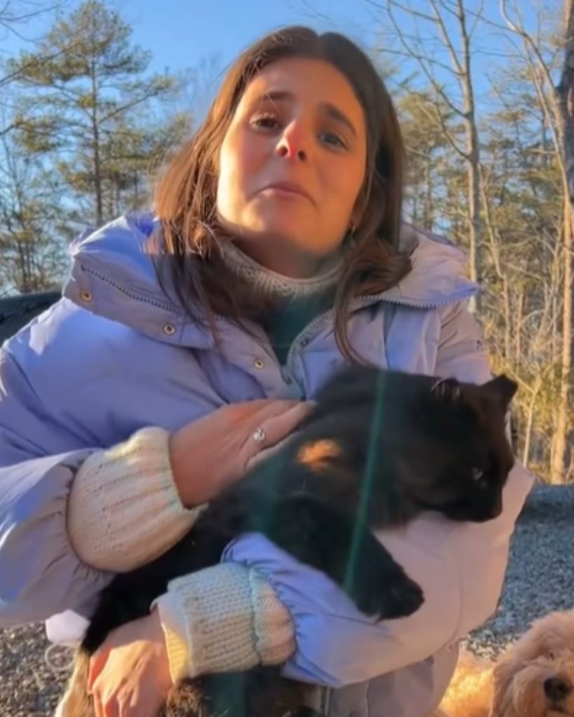 the girl is holding a black cat in her arms