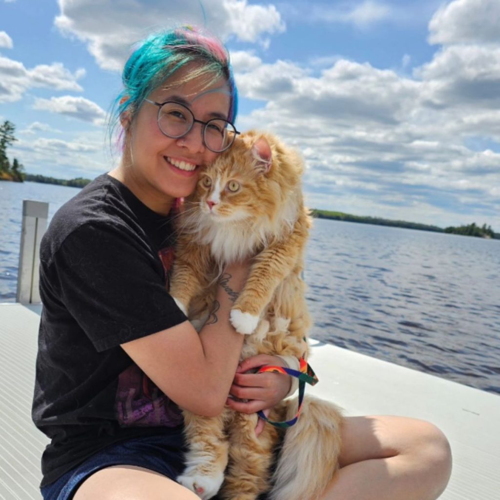 the girl sits on the pier and holds a cat in her arms