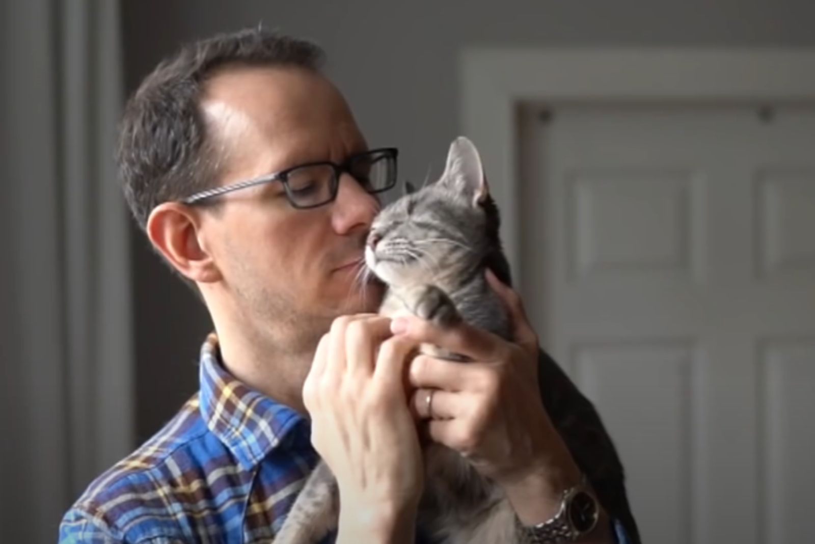 man cuddling with cat