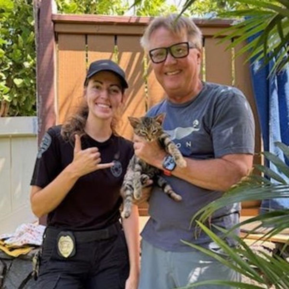 police officer and man posing with rescued cat