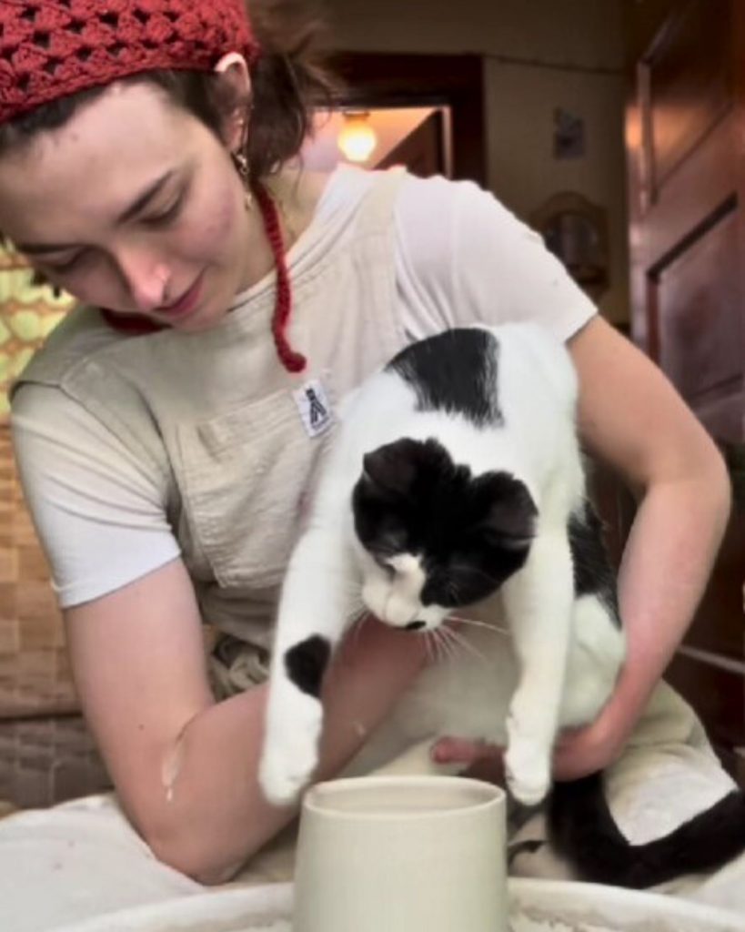 A girl holds a cat to watch a statue being made