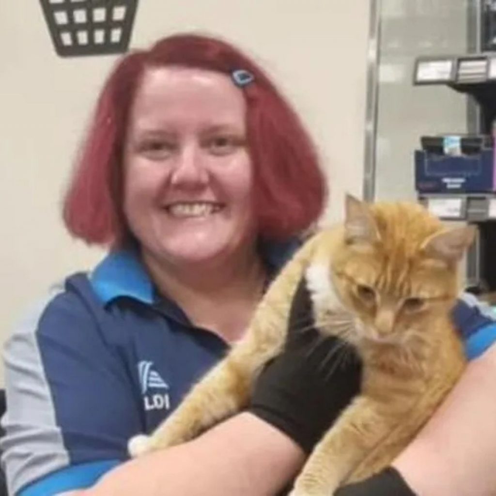 Smiling female worker holding a cat in her arms