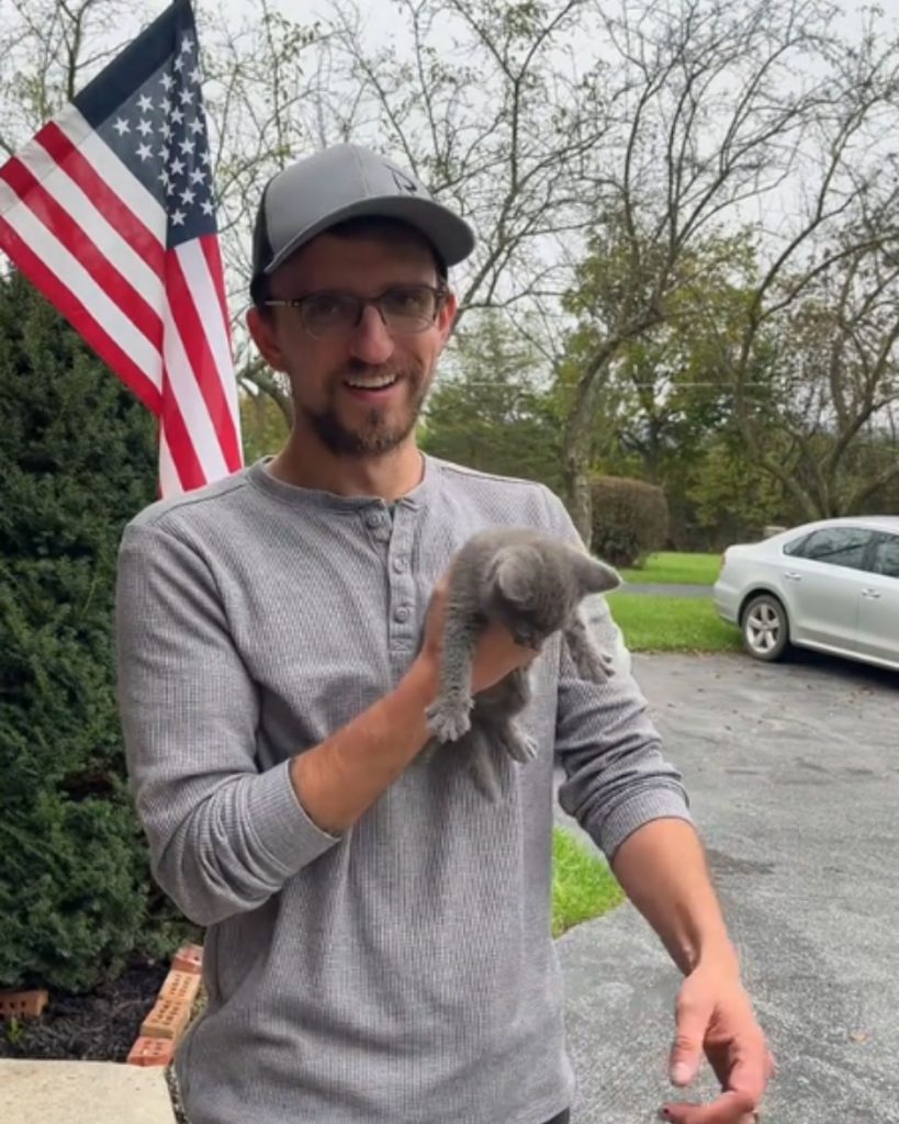 A man holds a small kitten in his hands