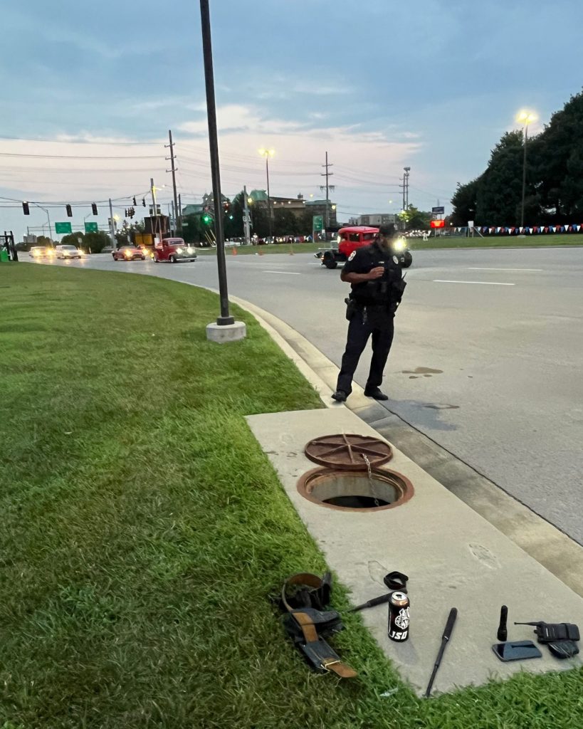 A police officer stands on the road next to a drain