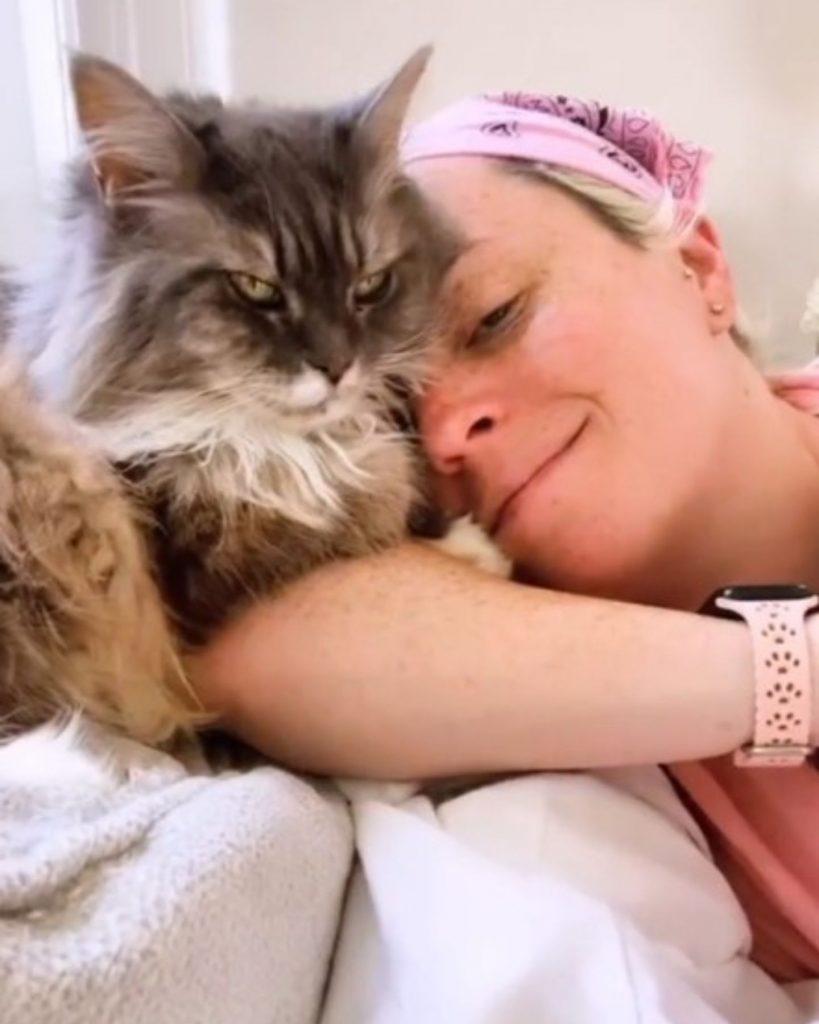 a girl takes a picture with a frowning cat