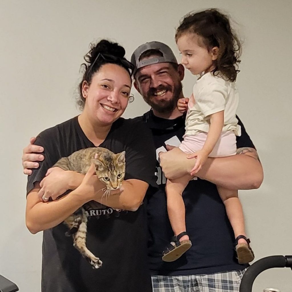 a smiling family takes a picture with a cat