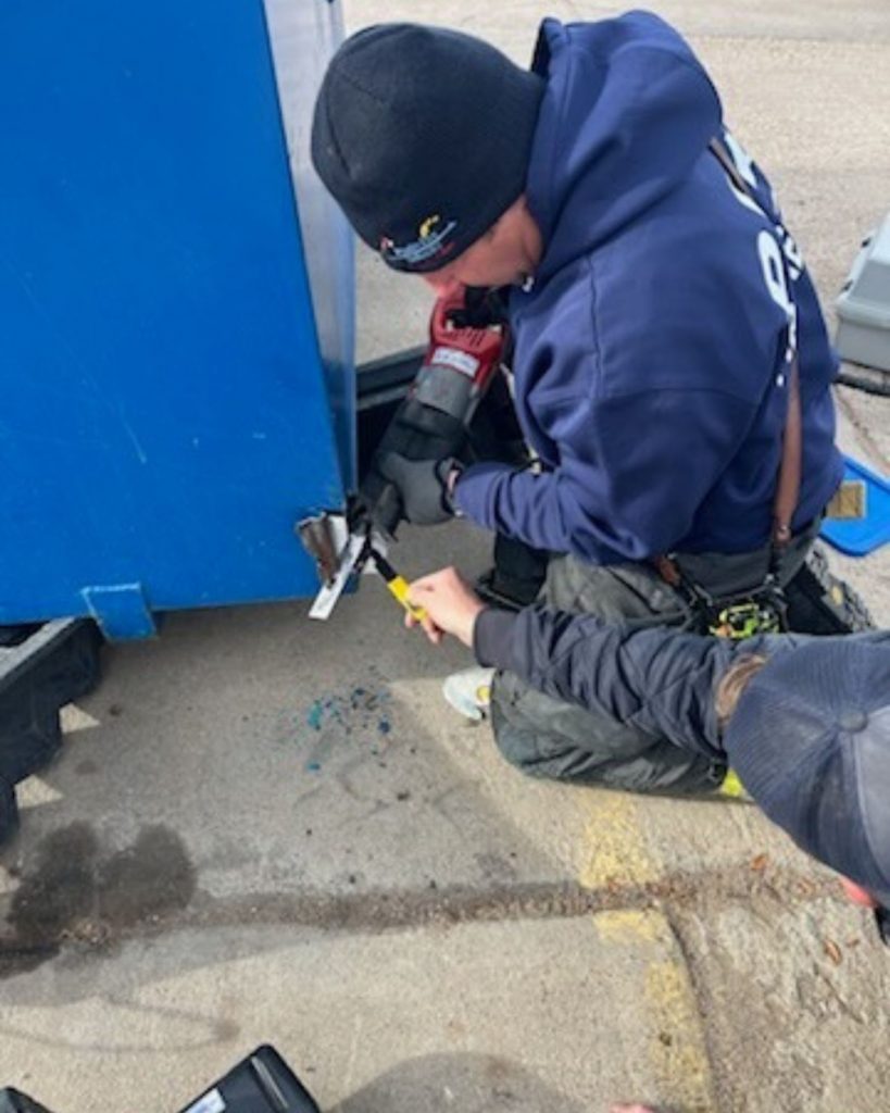 two men try to cut the container