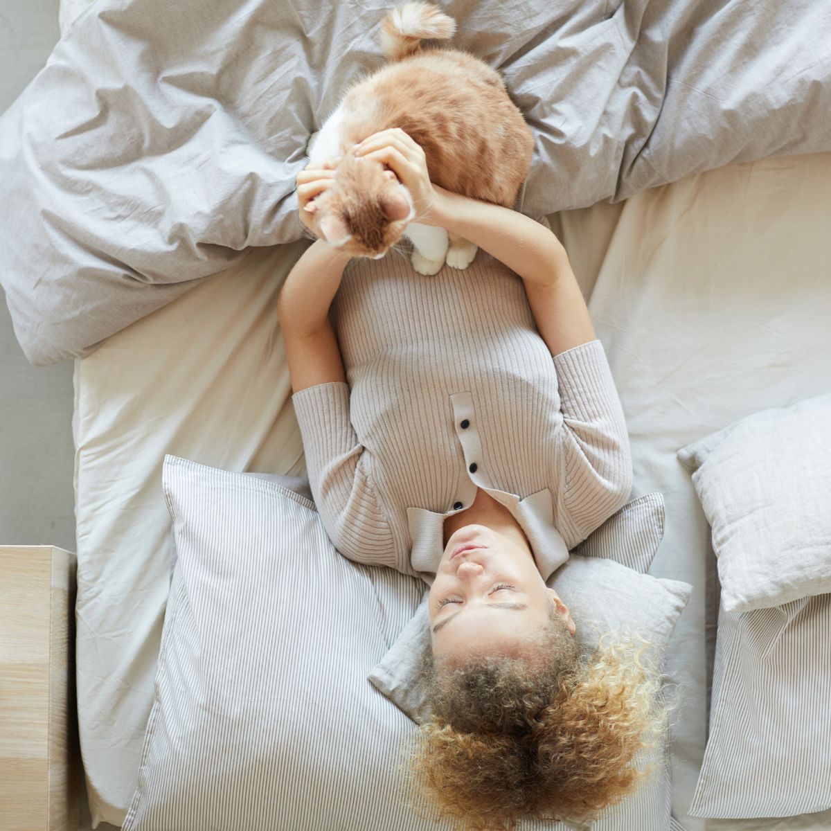 woman and cat lying in bed