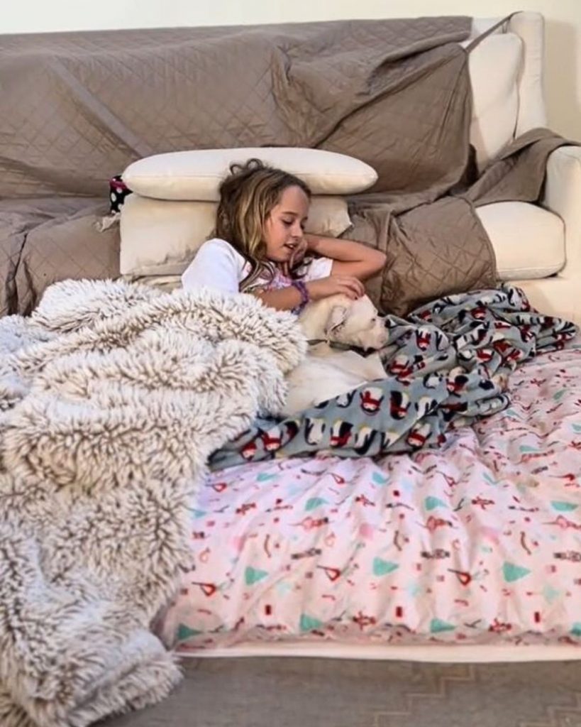 a girl and a dog lying in a bed