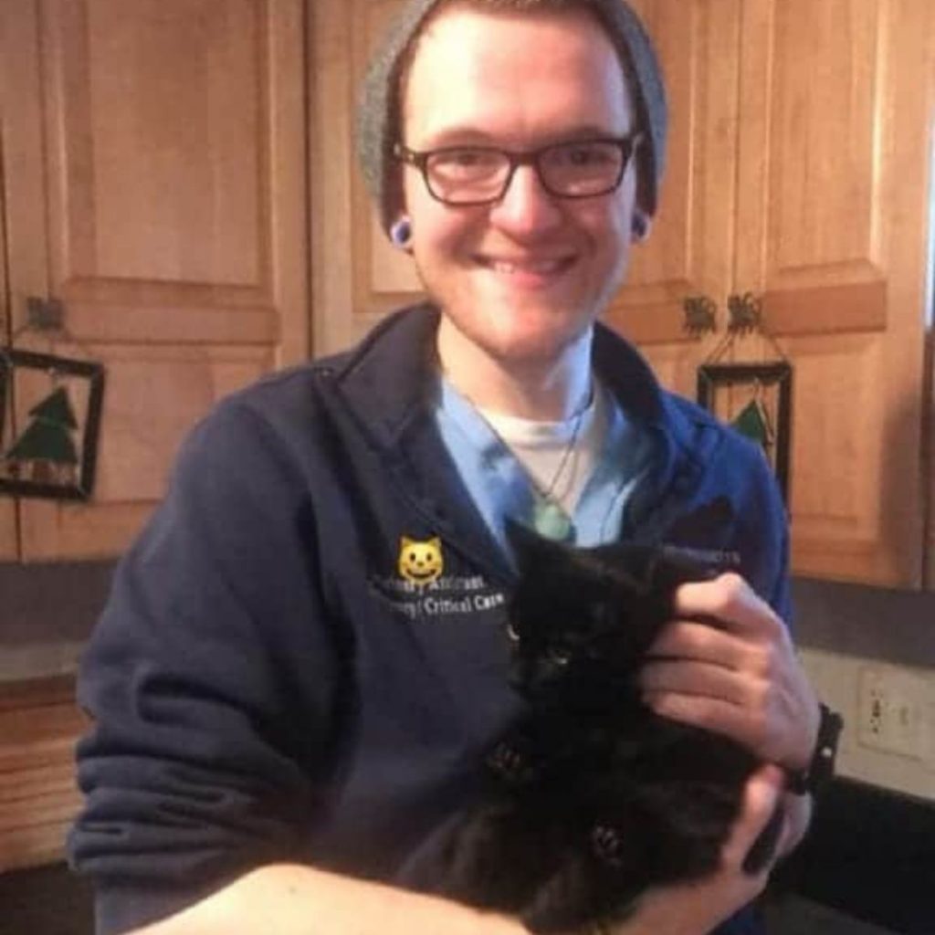 a man holding a black kitten