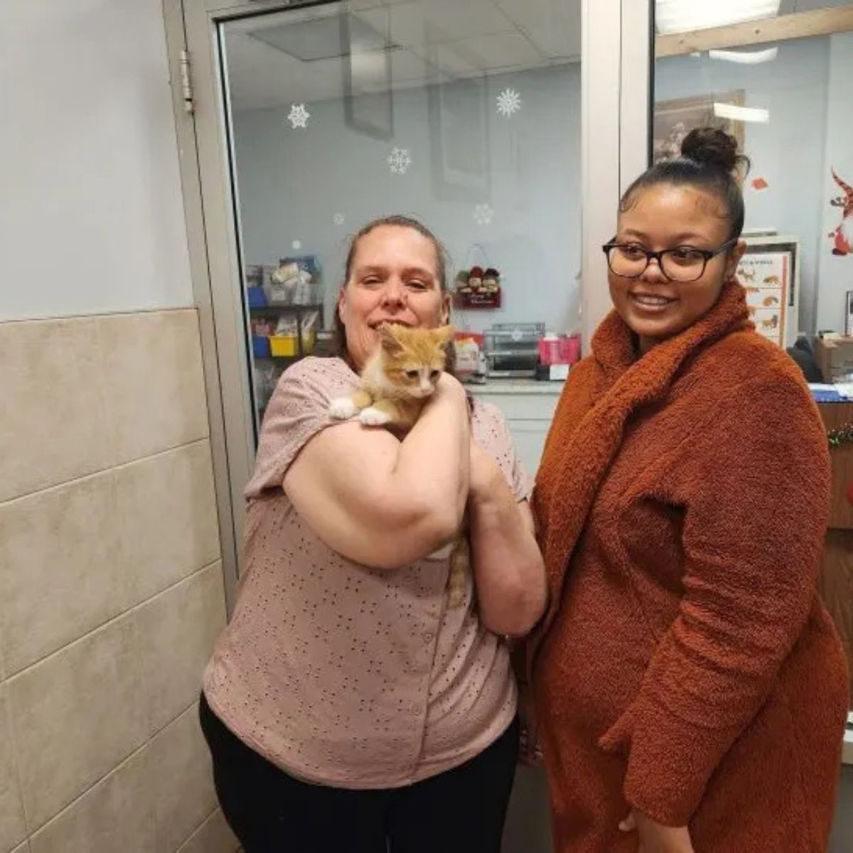 two women with an orange kitten