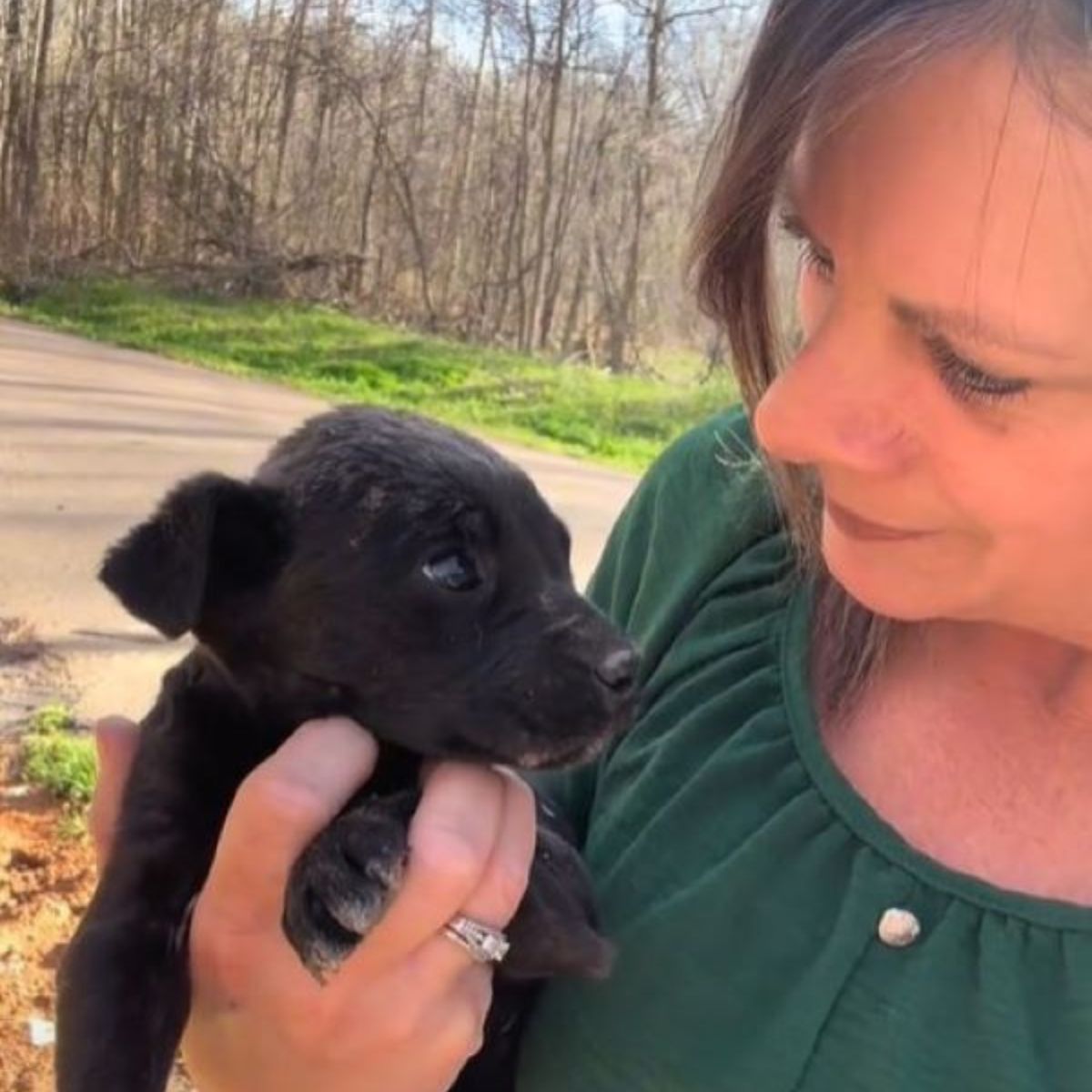 woman holding a black puppy