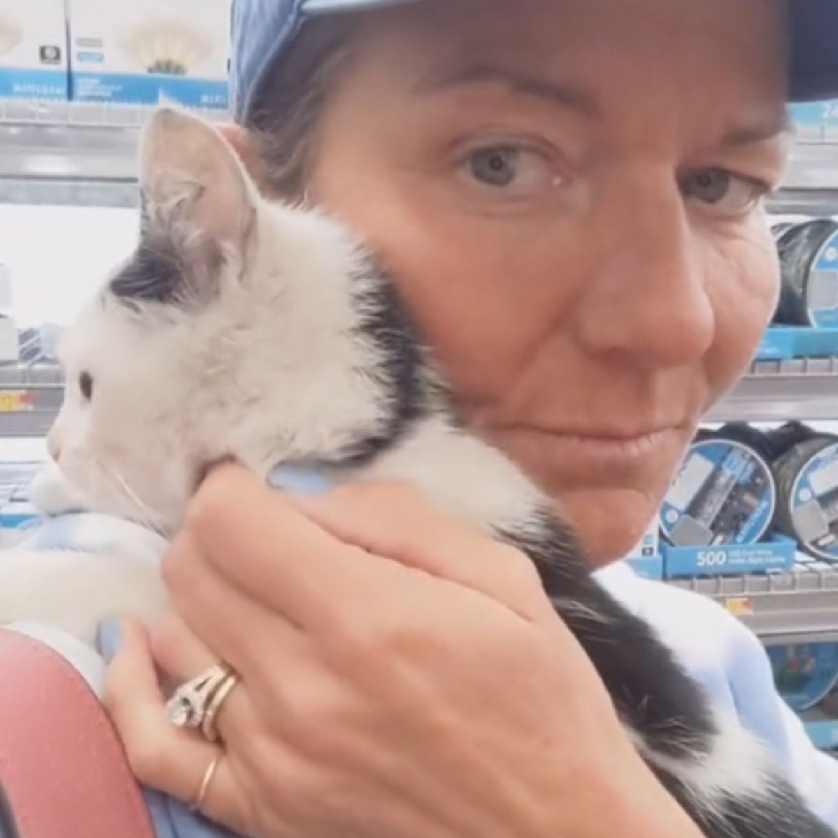 woman hugging a tiny black and white kitten